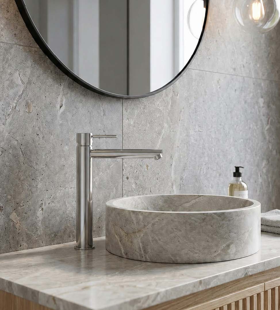 Plush Single lever High basin mixer over a carved stone basin with a round mirror